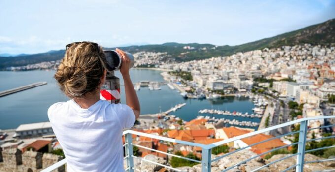 Une femme qui regarde la ville avec des jumelles vue de dos